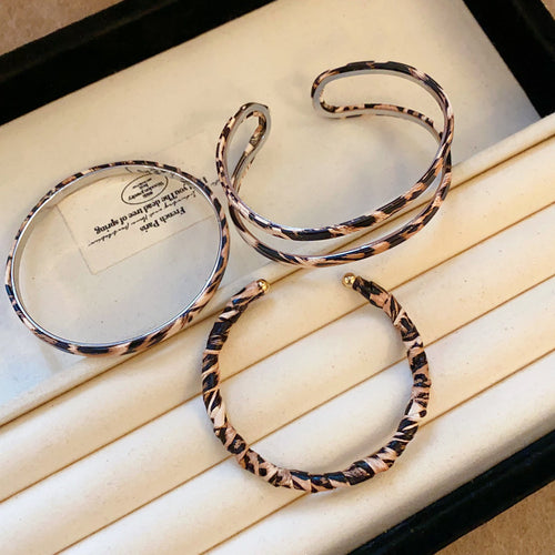 Three leopard print bangles double cuff closed and twisted on jewelry tray