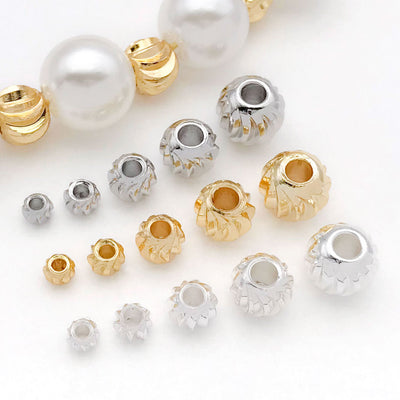 Front overview of curved blade fluted metal spacer beads arranged by finish and size