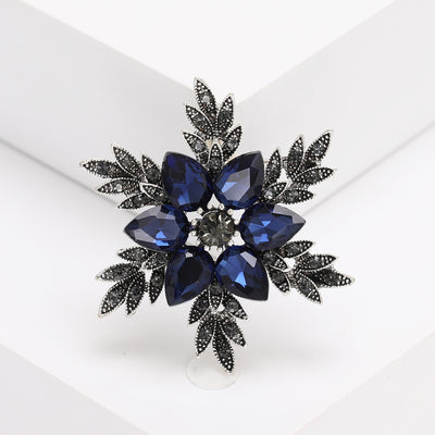 Deep Blue Crystal Flower Cluster Brooch with Dark Leaves front view on a light background