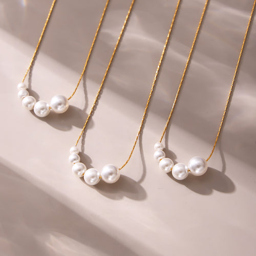 Three gold graduated shell bead pearl necklaces on beige fabric