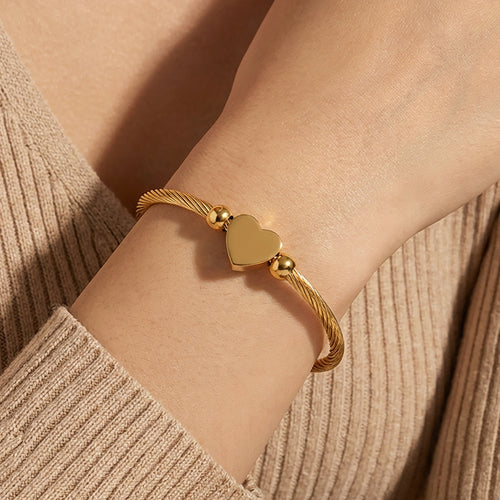Gold heart soft cable open bangle worn on wrist with sweater