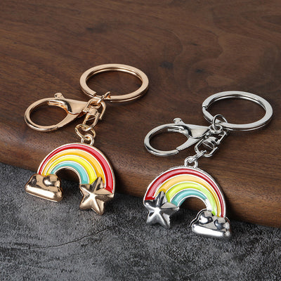 Gold-tone and silver-tone rainbow keychains displayed side by side on wood.