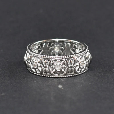 Silver wide filigree floral band ring front on dark surface