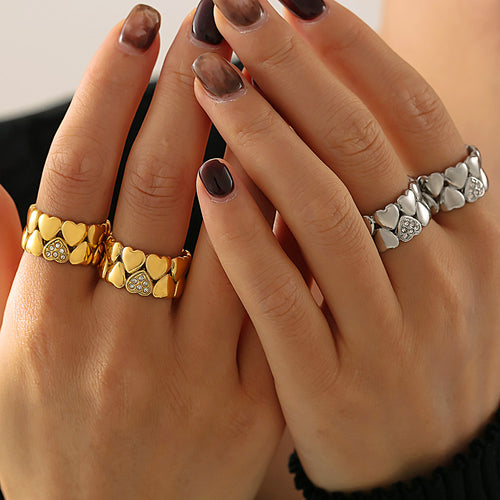 Hands wearing gold and silver heart band rings