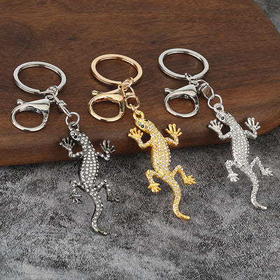Three rhinestone lizard keychains shown in silver, gunmetal, and gold finishes.