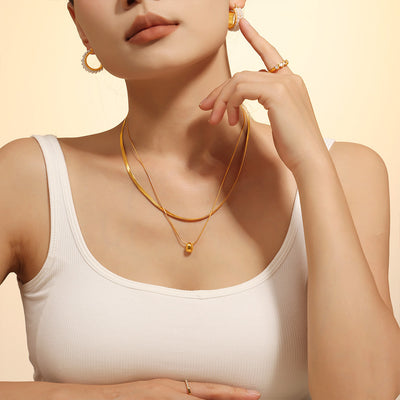 Gold double-layer herringbone bead necklace worn with white tank