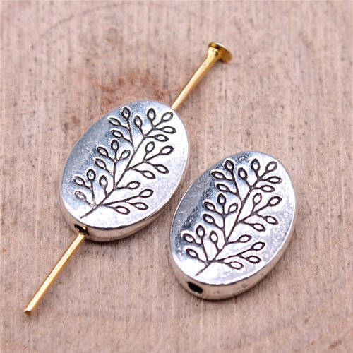 Alternate angle of oval tree pattern spacer beads showing raised tree motifs and oval profiles