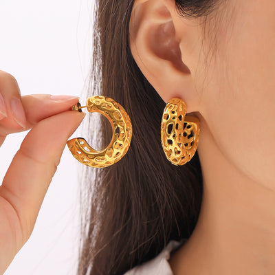 Model holding gold openwork C earring next to worn pair