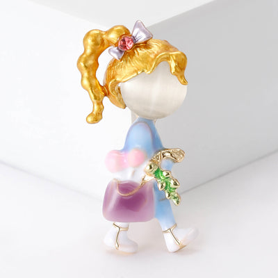 Front view of the handbag girl brooch showing a faceless girl carrying a pearl-look bag in pastel enamel clothing