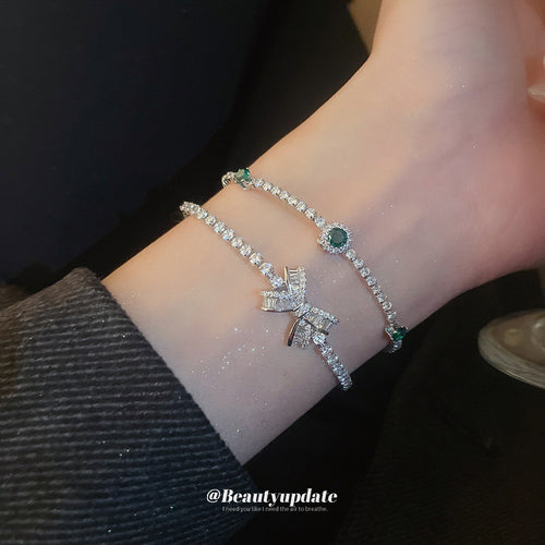 silver-tone clear crystal bow slider bracelet with an unlisted green style shown worn in a styled second view