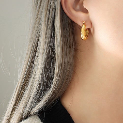 Side profile model wearing gold twisted chunky hoop earring