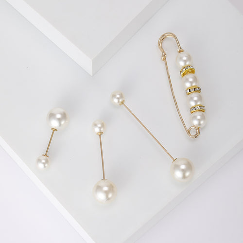 Four white pearl gold pins laid on white geometric blocks