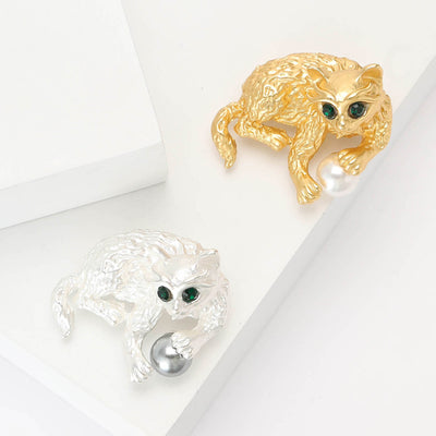 Gold and silver cat playing ball brooches on blocks