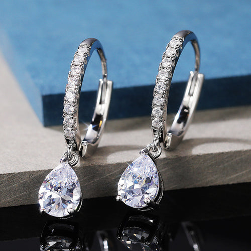 Silver teardrop pave hoop drop earrings on gray stone blue backdrop