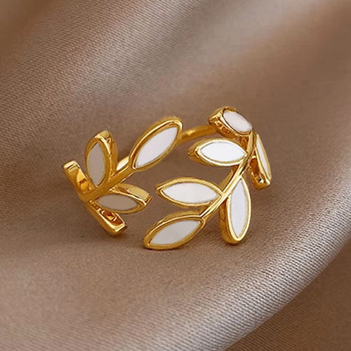 Top view of gold white enamel leaf open ring on champagne cloth