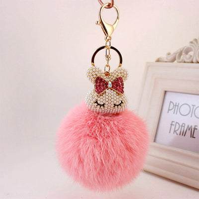 A soft pink fluffy ball hangs below a pearl-look beaded round-eared charm.