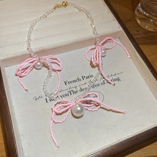 粉色蝴蝶结珍珠项链 shown in a styled product display