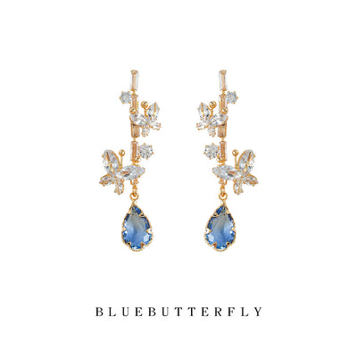 Gold-tone clear-stone-floral-branch blue-teardrop studs in the first product display.