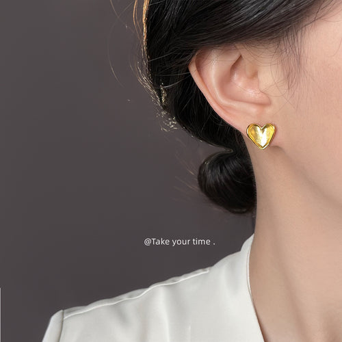 Matte gold heart stud earring worn on ear side profile