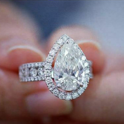 Pear halo ring held between fingers front-facing close-up
