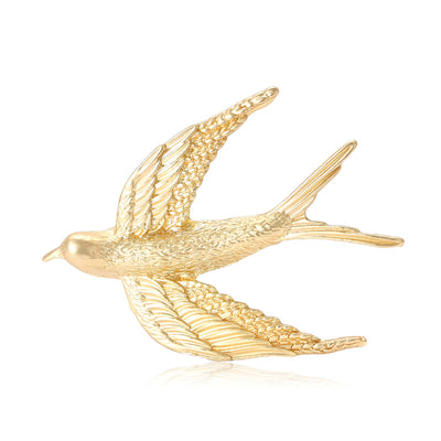 Front view of a flying swallow with finely textured wings and a matte gold-tone finish