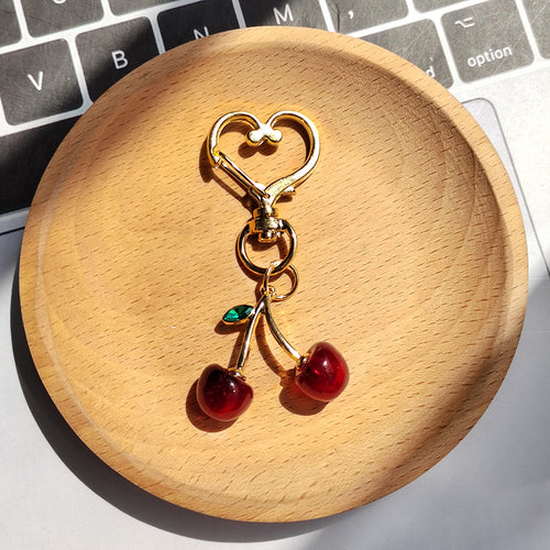 Dark red cherry keychain with one green leaf on gold heart lobster clasp