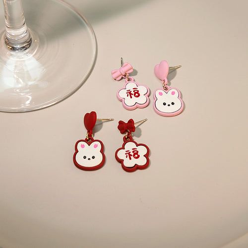 Red and pink asymmetric bunny Fu studs laid flat on cream surface