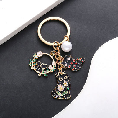 Front product photo of black cat heart flower wreath and pearl enamel keychain showing the pictured design arrangement