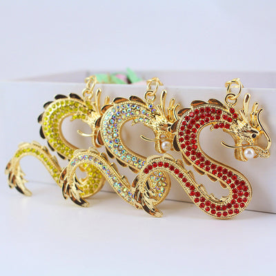 Three S-shaped dragon charms display red, iridescent, and yellow-green rhinestones.