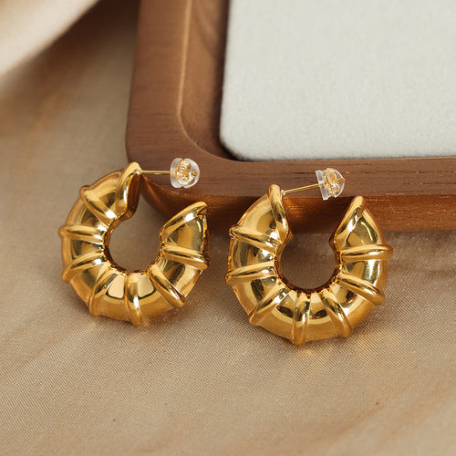 Gold bamboo segment hoops on wood tray and fabric