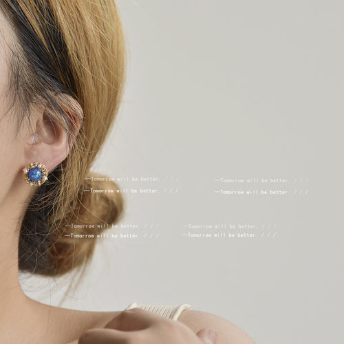 Model ear wearing gold filigree blue cabochon pearl halo stud earring