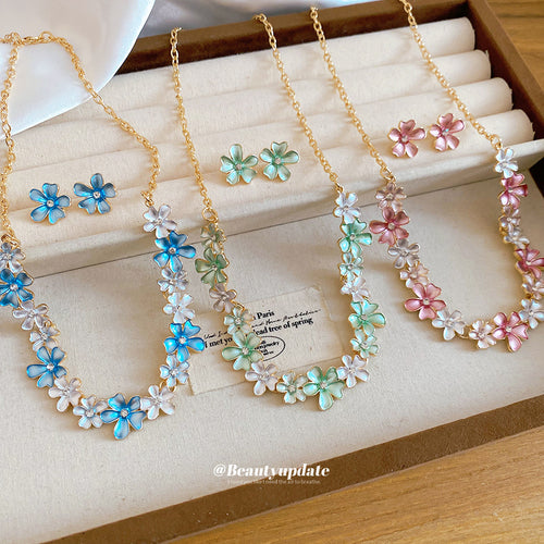 Three gold enamel daisy necklace and earring sets in blue green pink tray
