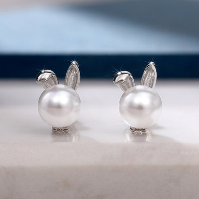 Pair of silver bunny-ear white pearl studs facing forward on stone
