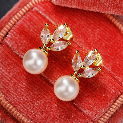 Gold marquise leaf faux pearl drop stud earrings on red velvet