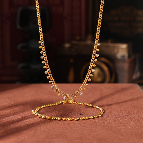 Gold necklace and bracelet with beads rhinestones on brown surface