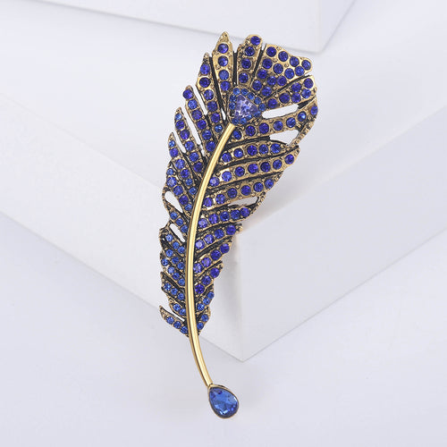 Blue rhinestone feather brooch on white geometric display