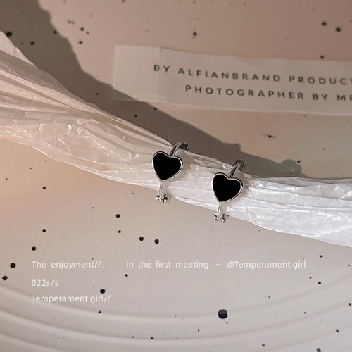 Black enamel heart huggies on crumpled white paper strip