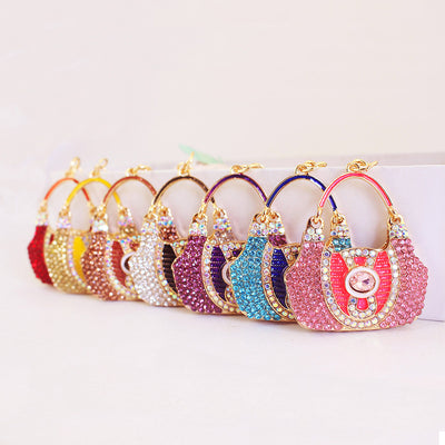 A row of handbag-shaped rhinestone charms in assorted colors.