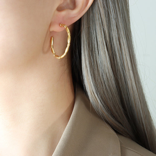 Gold bamboo segment open C hoop earring worn on ear