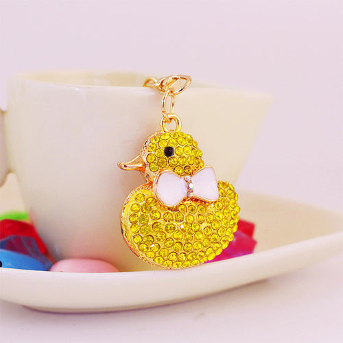 Front view of the yellow duck charm hanging beside a white cup