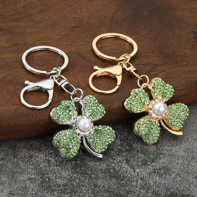 Gold-tone and silver-tone clover keychains displayed together on a wood surface.