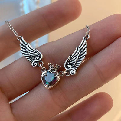 Antique silver crown heart wings necklace resting across palm fingers