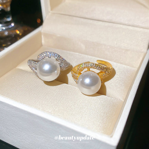 Silver and gold pearl open rings side by side in cream jewelry box