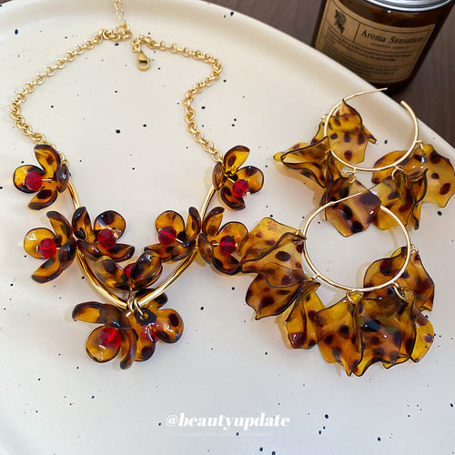 Tortoiseshell acrylic orchid necklace and petal hoop earrings on plate