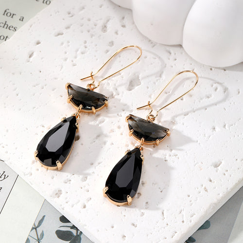 Black half-moon and teardrop crystal drop earrings on white stone