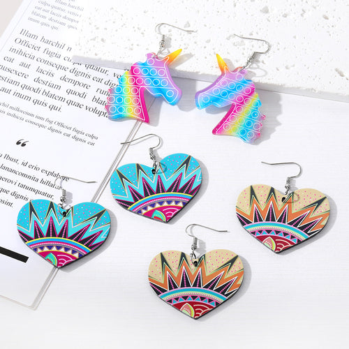 Assorted acrylic heart and rainbow unicorn drop earrings on book page