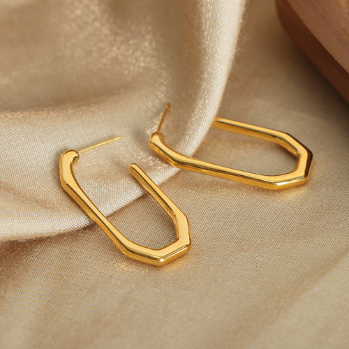 Pair of gold geometric U studs on beige satin