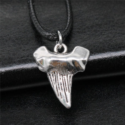 Close-up of shark tooth cord necklace showing a textured shark-tooth pendant on a black cord