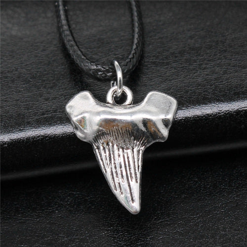 Close-up of shark tooth cord necklace showing a textured shark-tooth pendant on a black cord