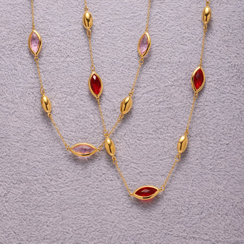 Flat lay pink and red marquise glass station necklaces on gray fabric